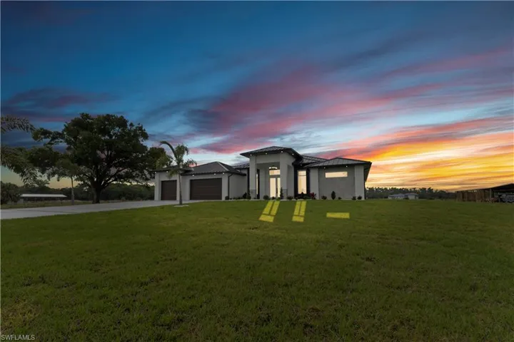 Prairie-style home with stucco siding, an attached garage, driveway, and a yard