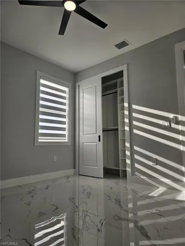 Unfurnished bedroom with marble finish floor, visible vents, a ceiling fan, a closet, and baseboards