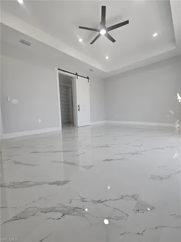 Empty room with visible vents, marble finish floor, baseboards, and ceiling fan