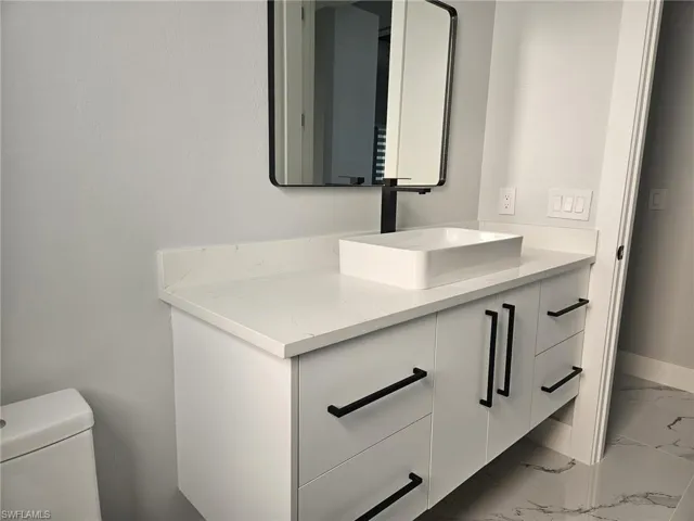 Bathroom featuring marble finish floor, toilet, vanity, and baseboards