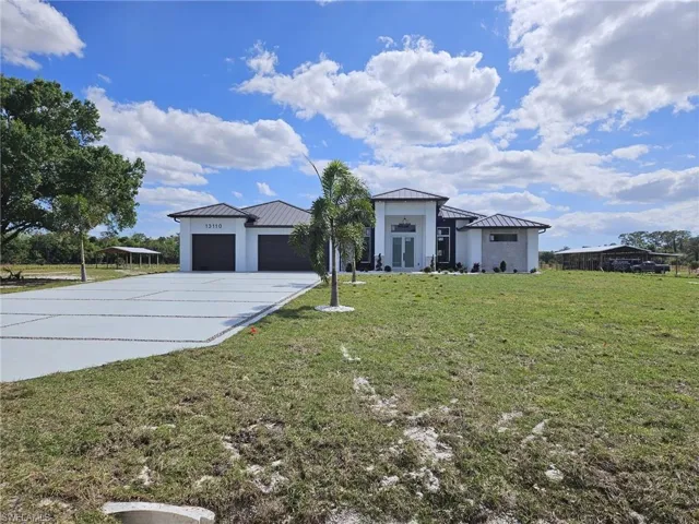 View of front of property featuring metal roof, a garage, a front yard, and a standing seam roof