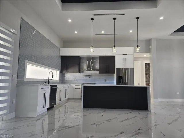 Kitchen with wall chimney range hood, modern cabinets, light countertops, stainless steel refrigerator with ice dispenser, and recessed lighting