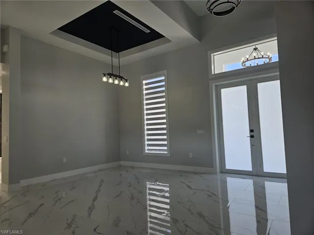 Foyer with marble finish floor, baseboards, a notable chandelier, and french doors