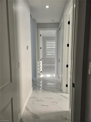 Hallway with baseboards, marble finish floor, and recessed lighting