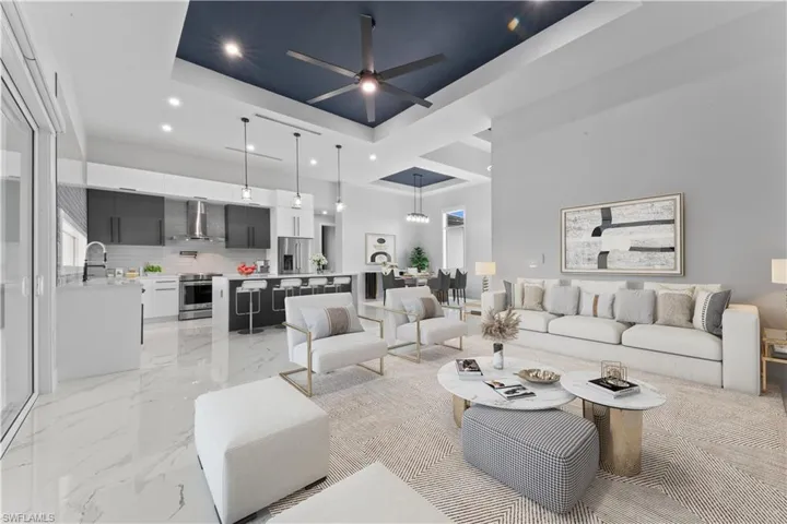 Living area featuring a tray ceiling, recessed lighting, marble finish floor, and ceiling fan