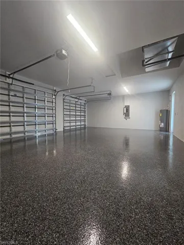 Garage featuring electric panel, water heater, and a garage door opener