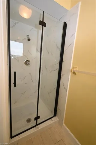 Enclosed shower stall featuring clear glass panels with matte black framing and hardware