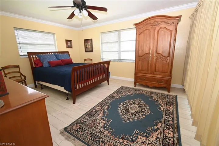Spacious room with light-toned tile flooring, crown molding, and a ceiling fan with integrated lighting