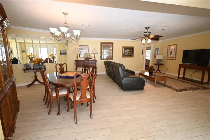 Open-concept living area featuring light-toned tile flooring, crown molding, and a neutral wall palette