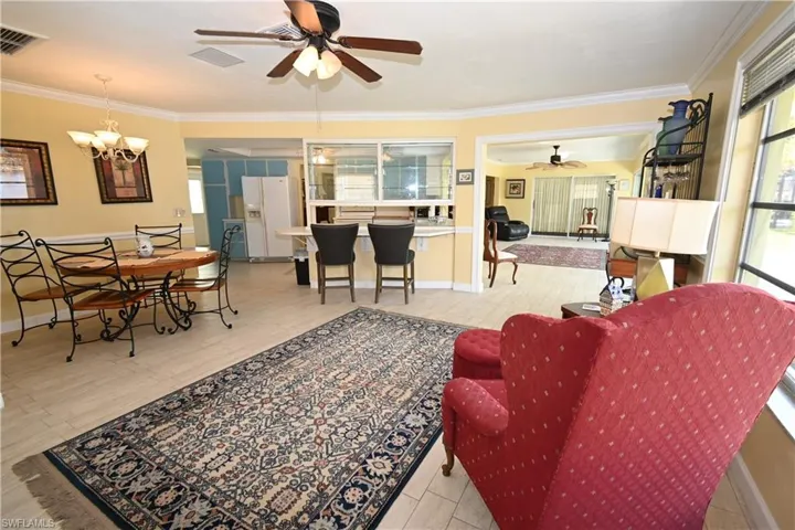 Open-concept living area featuring light-toned tile flooring and crown molding