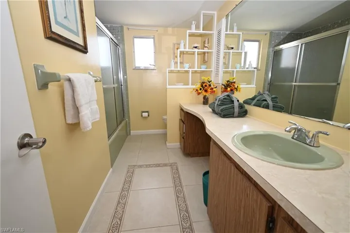 Bathroom featuring a wood-finish vanity with a light-toned countertop and an integrated green basin