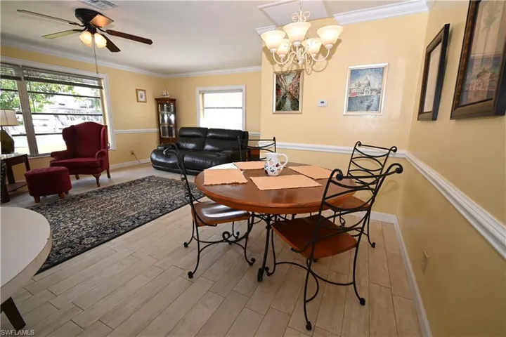 Open-concept living space featuring wood-finish flooring, crown molding, chair rail molding, and multiple windows