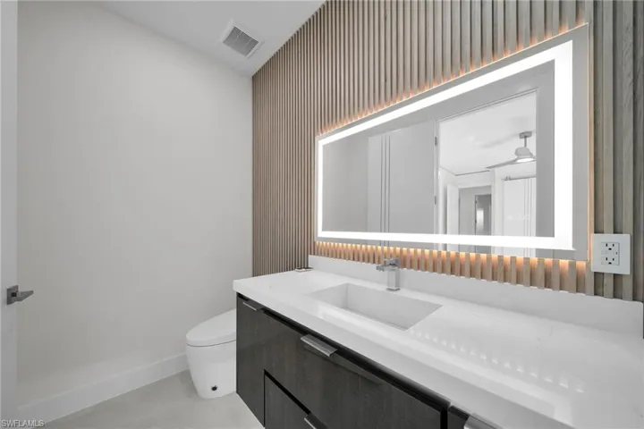 Bathroom with vanity, toilet, and ceiling fan