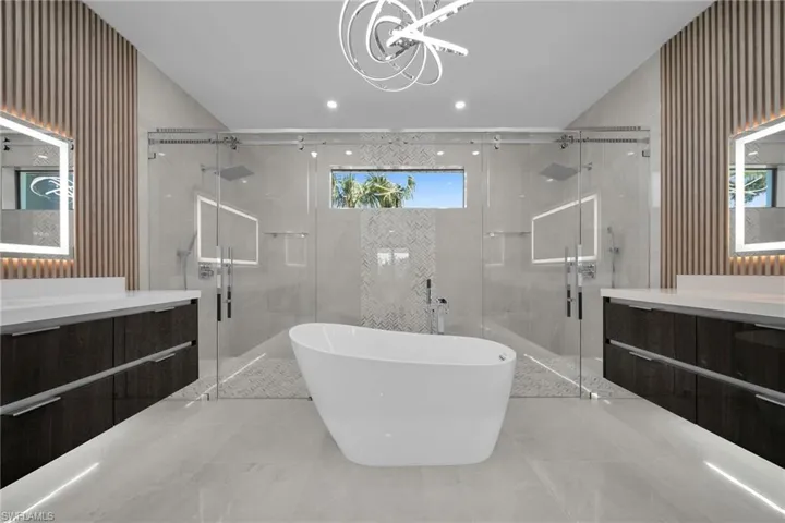 Bathroom featuring separate shower and tub, vanity, a healthy amount of sunlight, and a notable chandelier