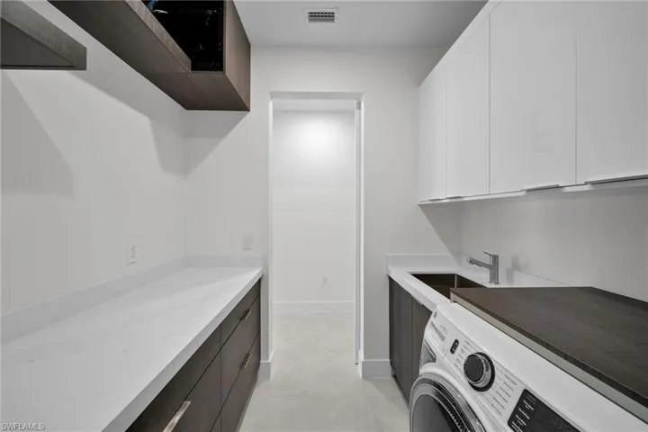 Laundry room with cabinets, washer / dryer, light tile patterned floors, and sink
