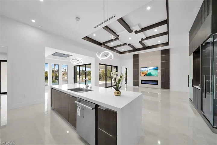 Kitchen with french doors, stainless steel dishwasher, sink, hanging light fixtures, and a large island