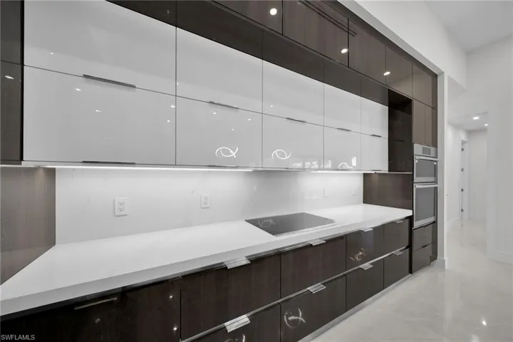 Kitchen with double oven, black electric cooktop, and white cabinets