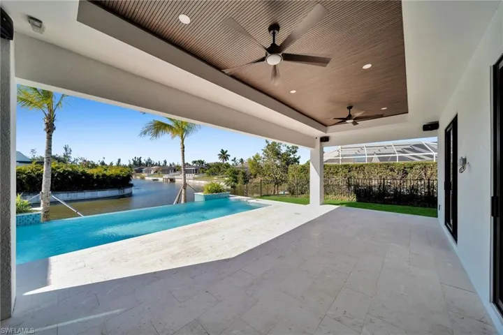 View of swimming pool with pool water feature, a water view, a patio, and ceiling fan