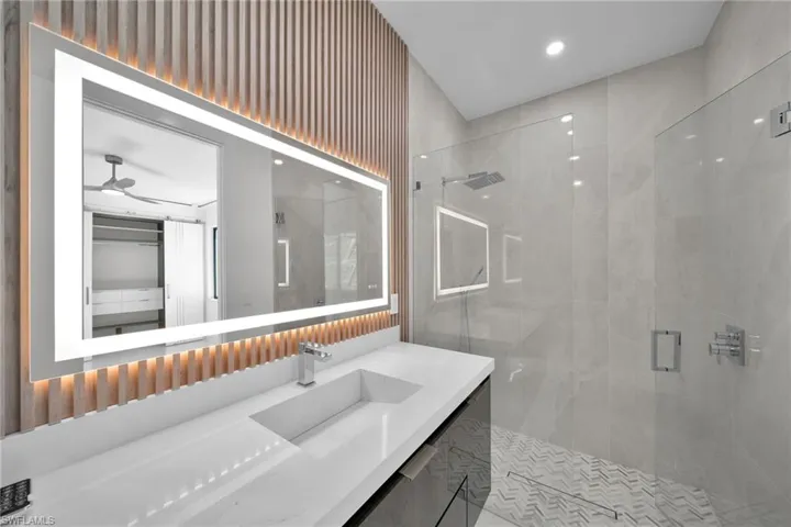 Bathroom featuring ceiling fan, vanity, and a shower with shower door