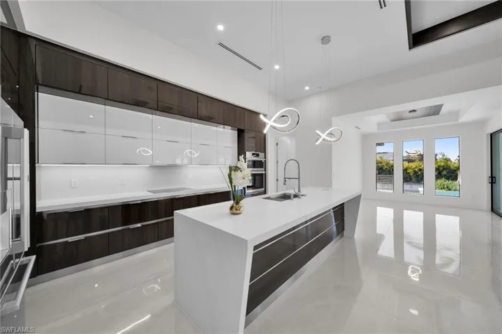 Kitchen featuring pendant lighting, sink, white cabinetry, and an island with sink
