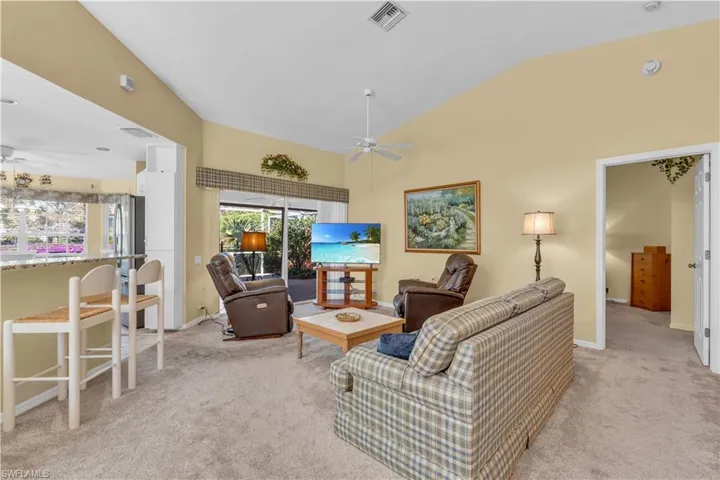 Carpeted living room featuring ceiling fan and vaulted ceiling