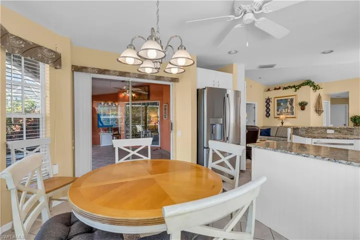 Dining room featuring ceiling fan with notable chandelier and light tile patterned floors