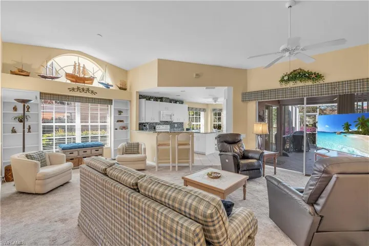 Carpeted living room featuring ceiling fan and high vaulted ceiling