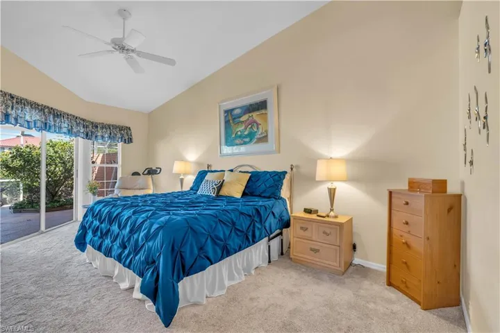Bedroom featuring ceiling fan, lofted ceiling, light carpet, and access to outside