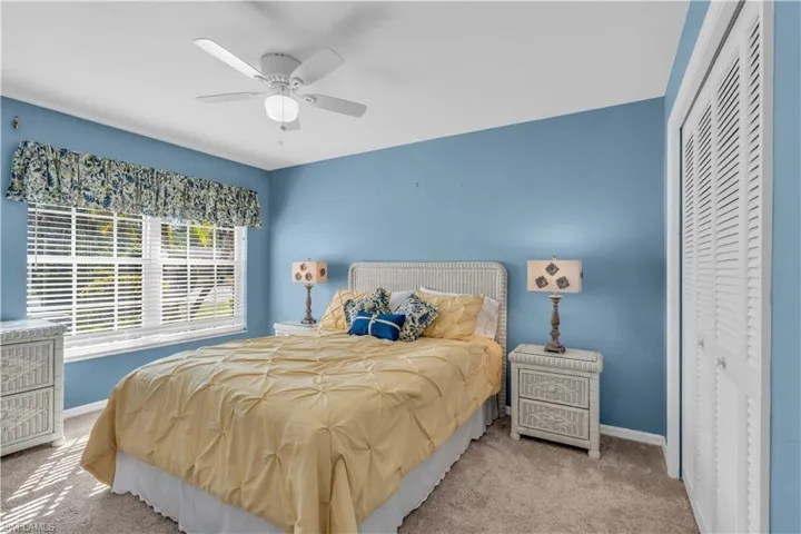 Carpeted bedroom featuring ceiling fan and a closet