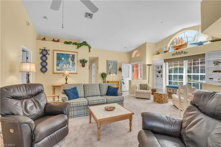 Carpeted living room featuring built in shelves and ceiling fan