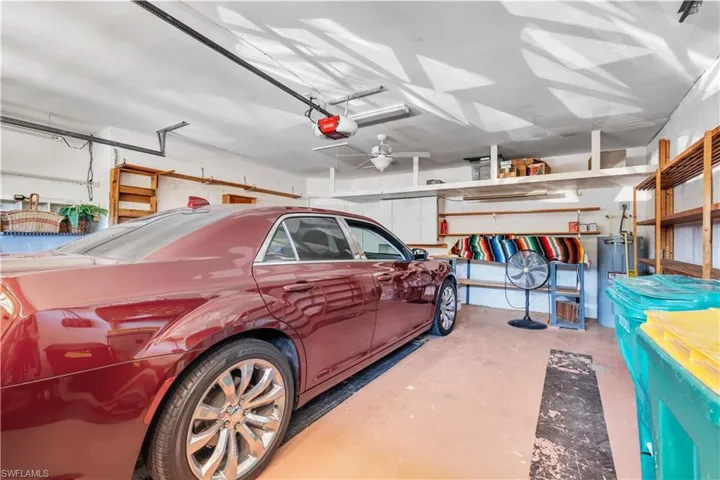 Garage featuring a garage door opener, ceiling fan, and water heater
