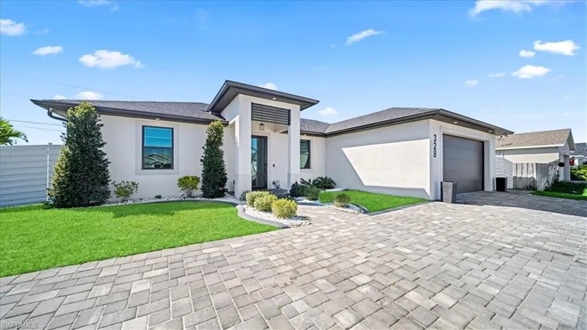 Prairie-style home featuring decorative driveway, stucco siding, and a garage