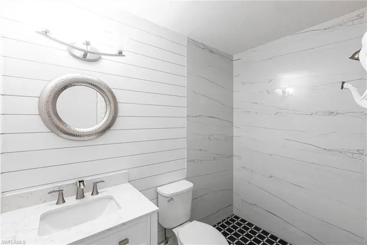 Bathroom featuring vanity, wood walls, and a shower