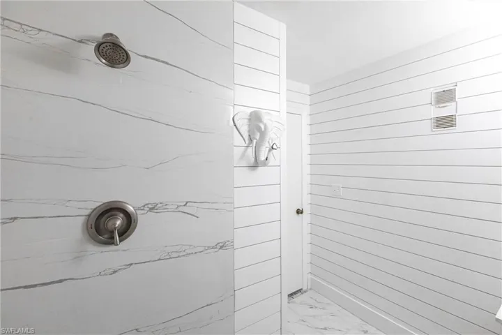 Full bathroom with a marble finish shower and marble finish flooring