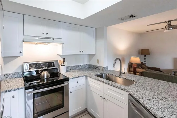 Kitchen with under cabinet range hood, appliances with stainless steel finishes, open floor plan, and new white cabinets with soft close drawers and quality construction with dovetail drawers.