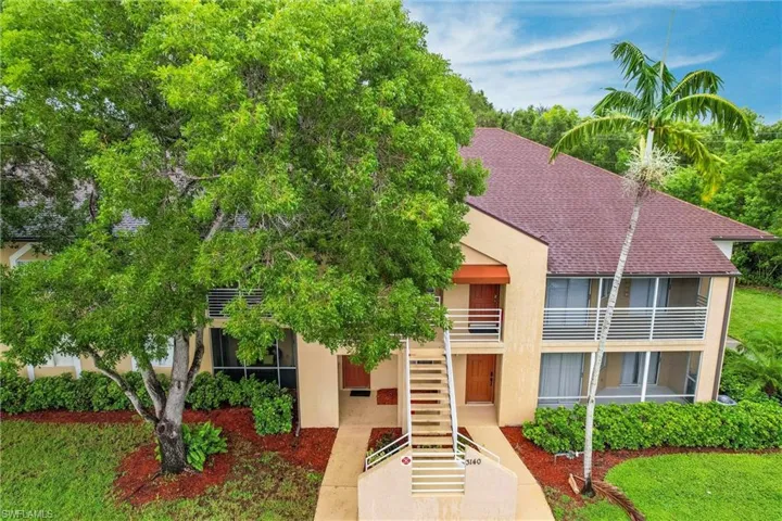 View of front of house featuring stairs, stucco siding, and a shingled roof