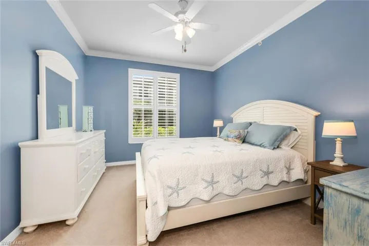 Carpeted bedroom featuring ornamental molding and ceiling fan