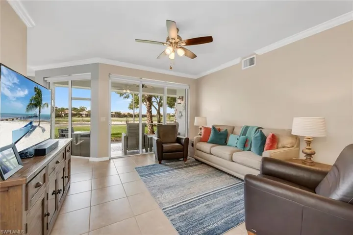 Living room with light tile patterned floors, crown molding, and a ceiling fan