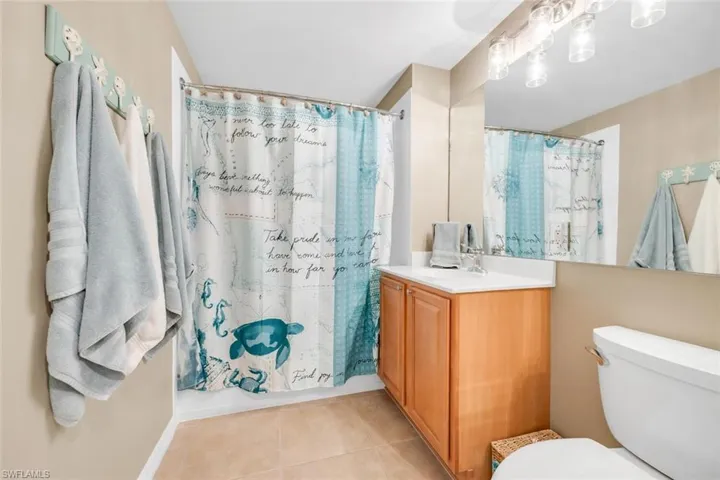 Bathroom featuring a shower with shower curtain, vanity, and light tile patterned floors