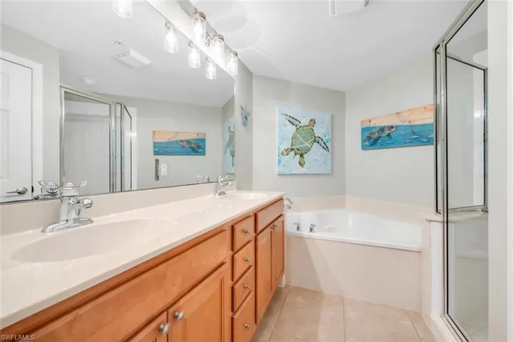 Full bathroom with double vanity, a stall shower, a garden tub, and light tile patterned flooring