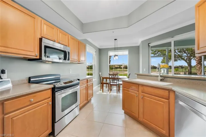 Kitchen with appliances with stainless steel finishes, pendant lighting, light tile patterned floors, and ornamental molding