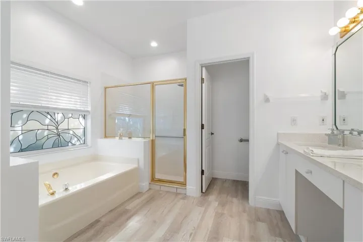 Bathroom with tile / wood-style flooring, vanity, and shower with separate bathtub