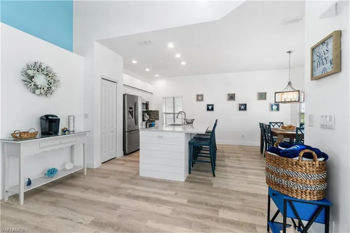 Kitchen with pendant lighting, sink, stainless steel appliances, white cabinets, and light wood-type flooring