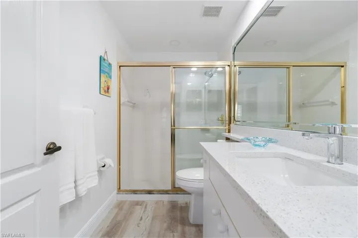 Bathroom with wood-type flooring, toilet, vanity, and walk in shower