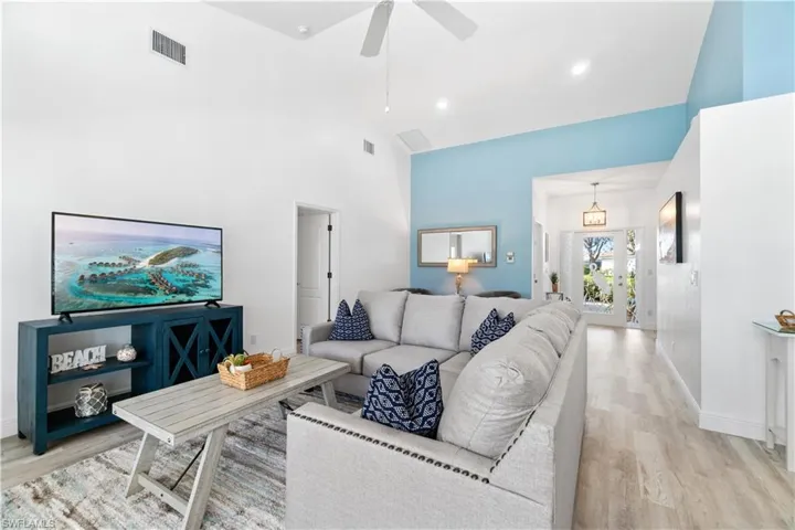 Living room featuring high vaulted ceiling, light hardwood / wood-style floors, and ceiling fan