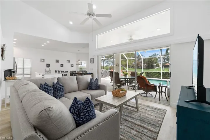 Living room featuring ceiling fan, a towering ceiling, and light wood-type flooring