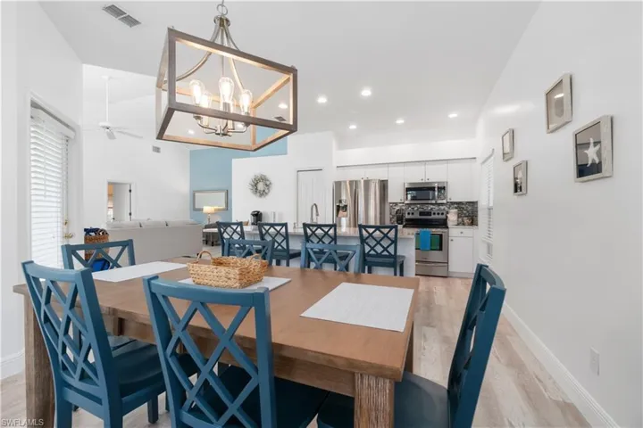 Dining space with ceiling fan with notable chandelier and light hardwood / wood-style flooring