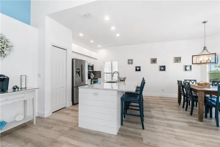Kitchen with appliances with stainless steel finishes, pendant lighting, an island with sink, sink, and white cabinets
