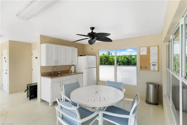 Community clubhouse kitchen featuring sink, ceiling fan, white cabinets, and white refrigerator