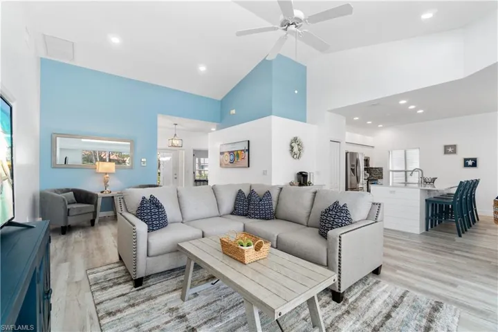 Living room with high vaulted ceiling, plenty of natural light, light hardwood / wood-style floors, and sink